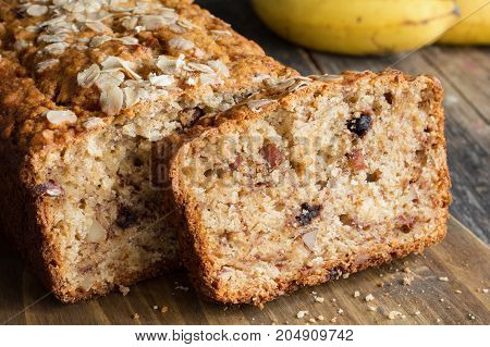 Homemade banana bread loaf with walnuts sliced on wooden cutting board. Closeup view, horizontal