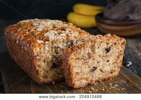 Homemade banana bread loaf with walnuts sliced on wooden cutting board. Closeup view, horizontal