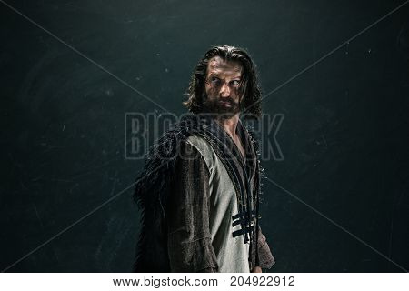 Actor in makeup, a poor man on black studio background. The bum in canvas rags. concept of vagrancy and survival