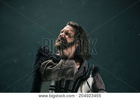 Actor in makeup, a poor man on black studio background. The bum in canvas rags. concept of vagrancy and survival