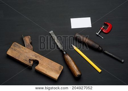 Joinery tools on dark wooden table background with blank business card.