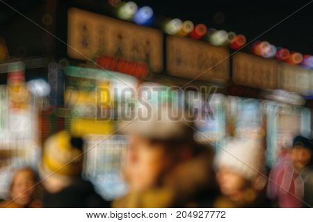 Illuminated Christmas fair kiosk market stall with loads of bootles with vin chaud - hot mulled wine and customers waiting in queue