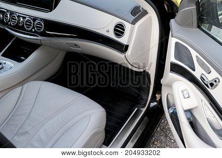 White leather interior of the luxury modern car. Leather comfortable white seats and multimedia. Steering wheel and dashboard. Automatic gear shift. Car interior details