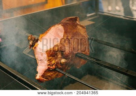 Large chunks of delicious pork hams cooked on an open fire. The street food. Food outdoors. Camping and cooking on a spit over the fire. Camping.