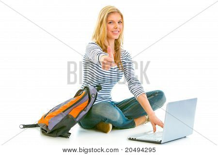 Seduto sul pavimento con zainetto e laptop sorridente teengirl showing thumbs up gesto isolato su wh