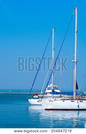 Two white sailing yachts. Sea port. Beautiful reflection in the water.