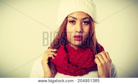 Winter clothing fashion concept. Beautiful young  woman wearing red woolen scarf white cap. Mixed race girl in wintertime clothes portrait studio shot