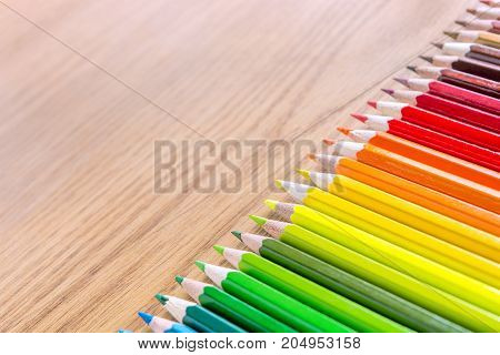 Many multicolored pencils on a wooden background. Different colored pencils with space for text. Copyspace. Back to school.