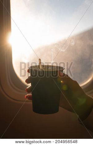 Girl is holding a glass of coffee in aircraft.