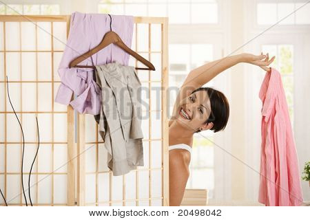 Felice giovane donna vestire in su, guardando fuori dietro il pannello di medicazione, rivelando la camicia rosa.