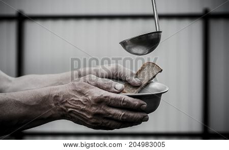 Female hand holding a ladle. The man in the hands holding a plate and a piece of bread.