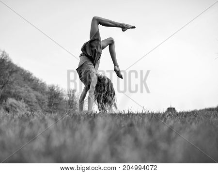 Young woman doing somersault on grass. Sport and leisure freedom