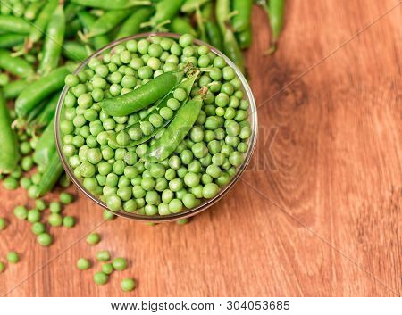 Fresh Green Peas Close Up On Wooden Background. Vegetables From The Garden. Blanks For Autumn, Or Wi