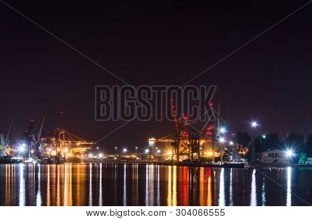 Seaport At Night - Port Quays And Transhipment Terminals In Colored Lights