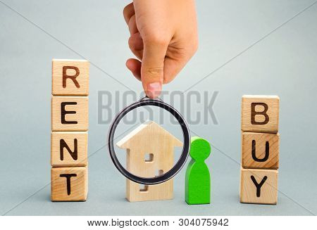 Wooden Blocks With The Word Rent Or Buy And A Person Stands Near The House. Make The Right Decision.