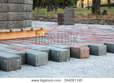 Paving The Footpath With Gray And Red Tiled Cubes.