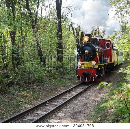 Steam Locomotive Going Through The Park And Blowing Off The Steam Out Of The Whistle