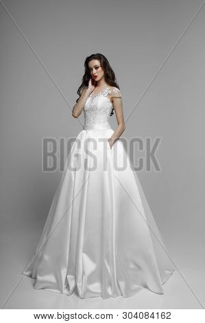 Frontal View Of A Brunette Model In Wendding Dress, Poses Tender In Studio, Isolated On A White Back