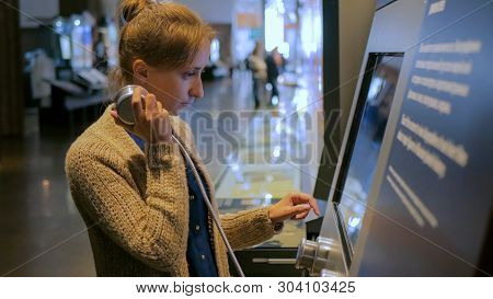 Woman Touching Interactive Display, Using Headphones And Listening Audio Guide At Modern Jewish Hist