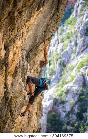Rock Climbing And Mountaineering In The Paklenica National Park. A Woman Overcomes A Challenging Cli