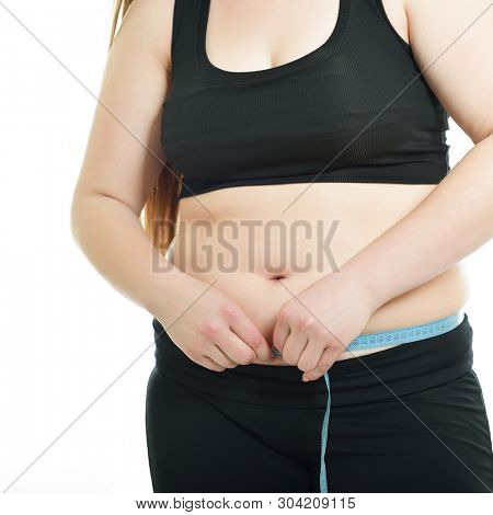 Overweight young woman measuring her waist, isolated over white background. Overeating xl size woman with measuring tape