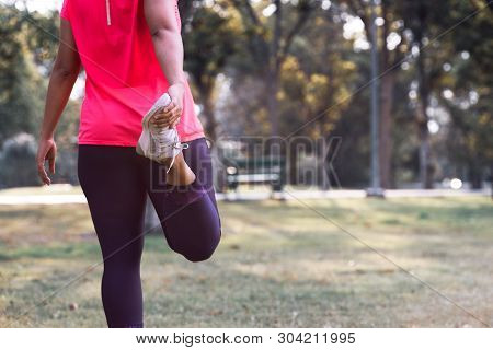 Sport Woman Stretching Leg Muscle Preparing For Running In The Public Park Outdoor. Close Up Of Fema