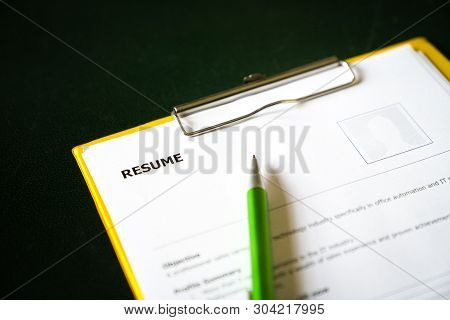 Resume On A Clipboard With Office Table Background. A Hiring Or Employment Concept