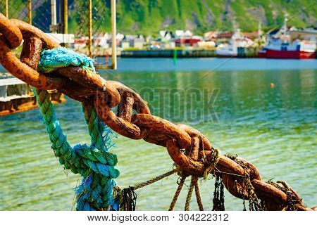 Rusty Old Metal Chain Links In Port. Marine Details. Bleik Village In The Background.