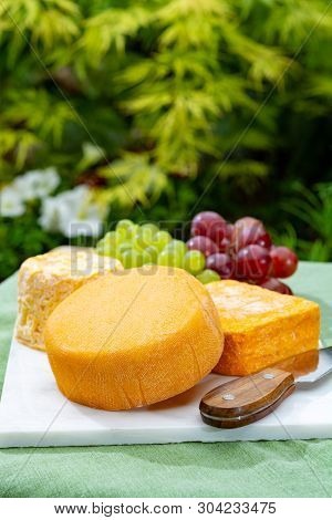 French Cheeses Collection, Yellow  Le Peche Des Bons Peres Cheese Served With Grapes On Marble Plate