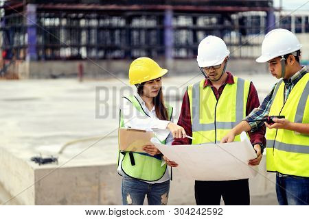 Foreman 3 People Are Held A Blueprint To Discuss The Construction Structure.woman Engineers Wear Saf
