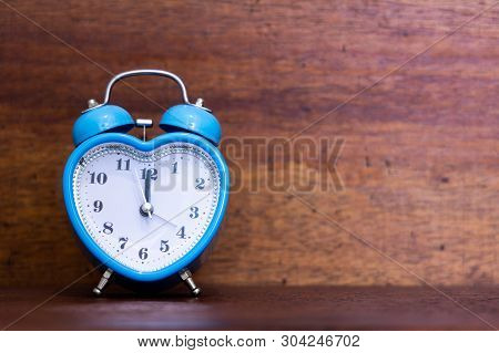 Heart Shaped Alarm Clock On Wooden Background. Time Is Twelth O Clock