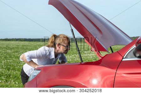 Woman Expresses Bewilderment When She Looks Under Hood Of Car.