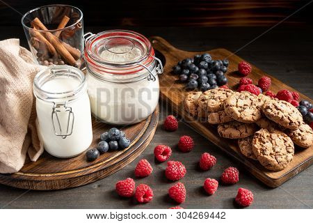 Milk, Cinnamom, Flour In Sealed Jars, Biscuits And Berries Placed On Wood