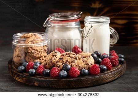 Milk, Cookies, Flour Recipients And Forest Fruits Placed On Rounded Wooden Platter