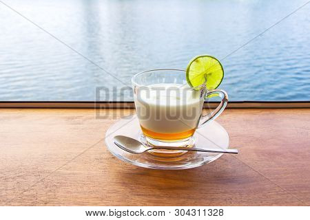 Lemon Yogurt Fresh Milk In A Clear Glass Placed On A Brown Wooden Table With Sea Water Surface Backg