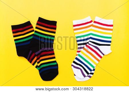 Two Pair Of Black And White Textile Cotton Socks With Striped Bright Colorful Pattern Over Yellow Ba