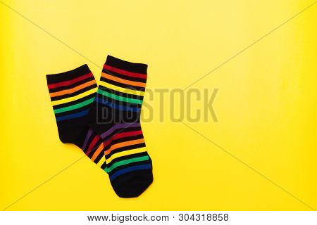 Black Textile Cotton Socks With Striped Bright Colorful Pattern Over Yellow Background With Copy Spa