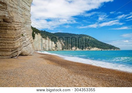 Beautiful Wild Beach With Azure Sea, Waves With White Foam And Pebbles On The Shore In Gargano Natio