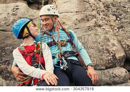 Young Couple In Love Climbers. Man And Woman Hanging On A Rock On Ropes. Climbing, Extreme Sport