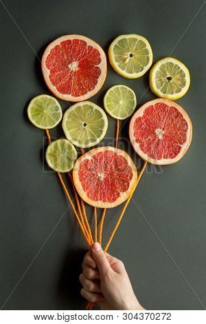 A Female Hand Holds Air Balloons With Orange Threads Made Of Citrus Slices (lemon, Lime, Orange, Gra