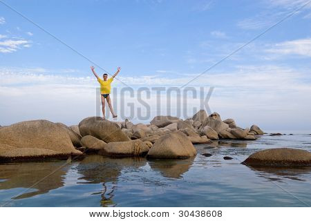 Middelhavet.Radisson ung mand costs(stands) på en leg(foot) på en sten.