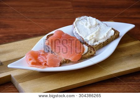 Slices Of Bread With Salmon Fillet And Quark On A White Plate