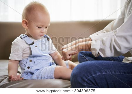 Mother Hiding Ball In One Hand And Asking Son To Choose Between Fists