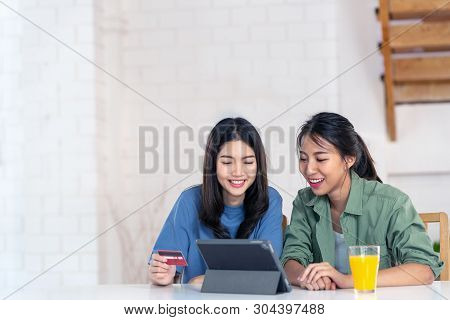 Candid Of Young Attractive Asian Two Girls Sitting At Home Holding Discount Credit Card In Hand Payi