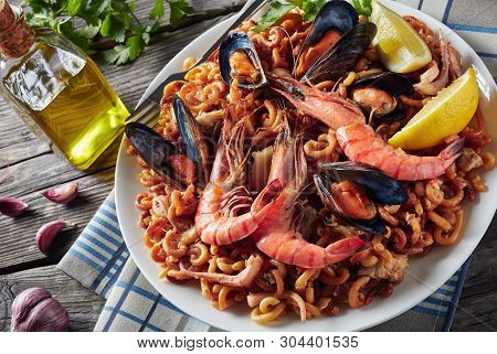 Close-up Of Spanish Fideua, A Noodle Paella With King Prawns, White Fish Meat, Calamari, Mussels Ser