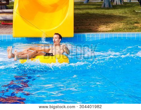 Funny Excited Man Enjoying Summer Vacation In Water Park Riding Yellow Float Laughing.