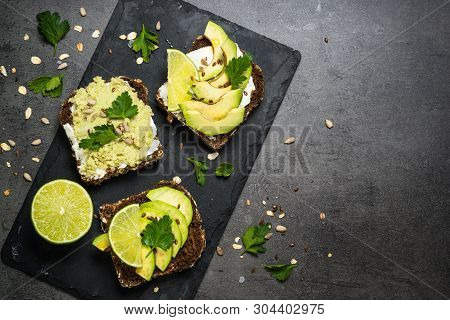 Sandwiches With Avocado And Cream Cheese With Grain Bread And Seeds. Black Slate Background, Top Vie
