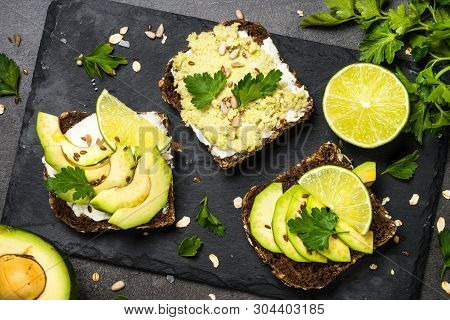 Sandwiches With Avocado And Cream Cheese With Grain Bread And Seeds. Black Slate Background, Top Vie