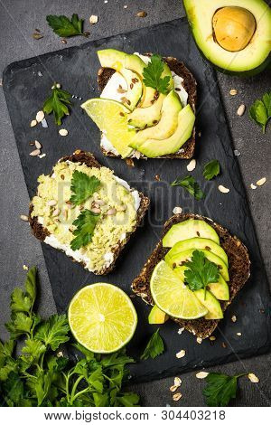 Sandwiches With Avocado And Cream Cheese With Grain Bread And Seeds. Black Slate Background, Top Vie