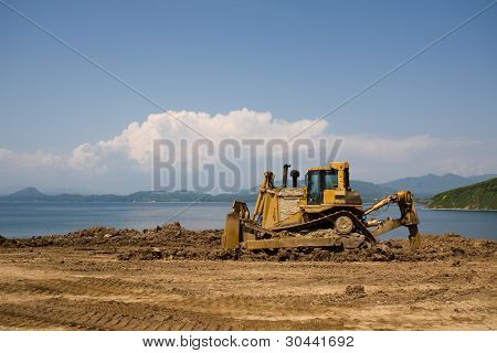Buldozer na staveniště.Na pozadí moře.